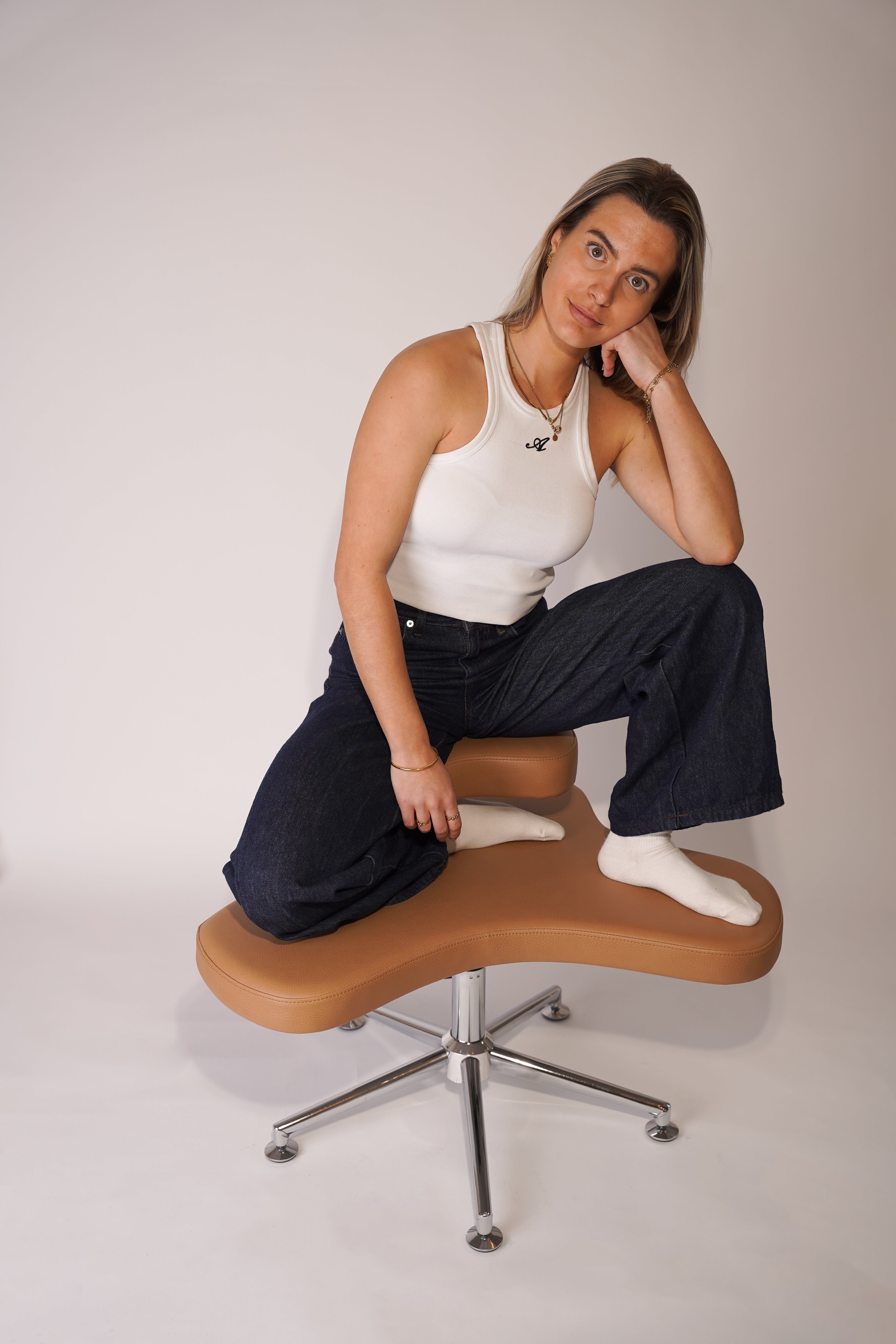 Model Posed auf Schneidersitz Stuhl Yogi Seat, den Kopf abgestützt auf der linken Hand